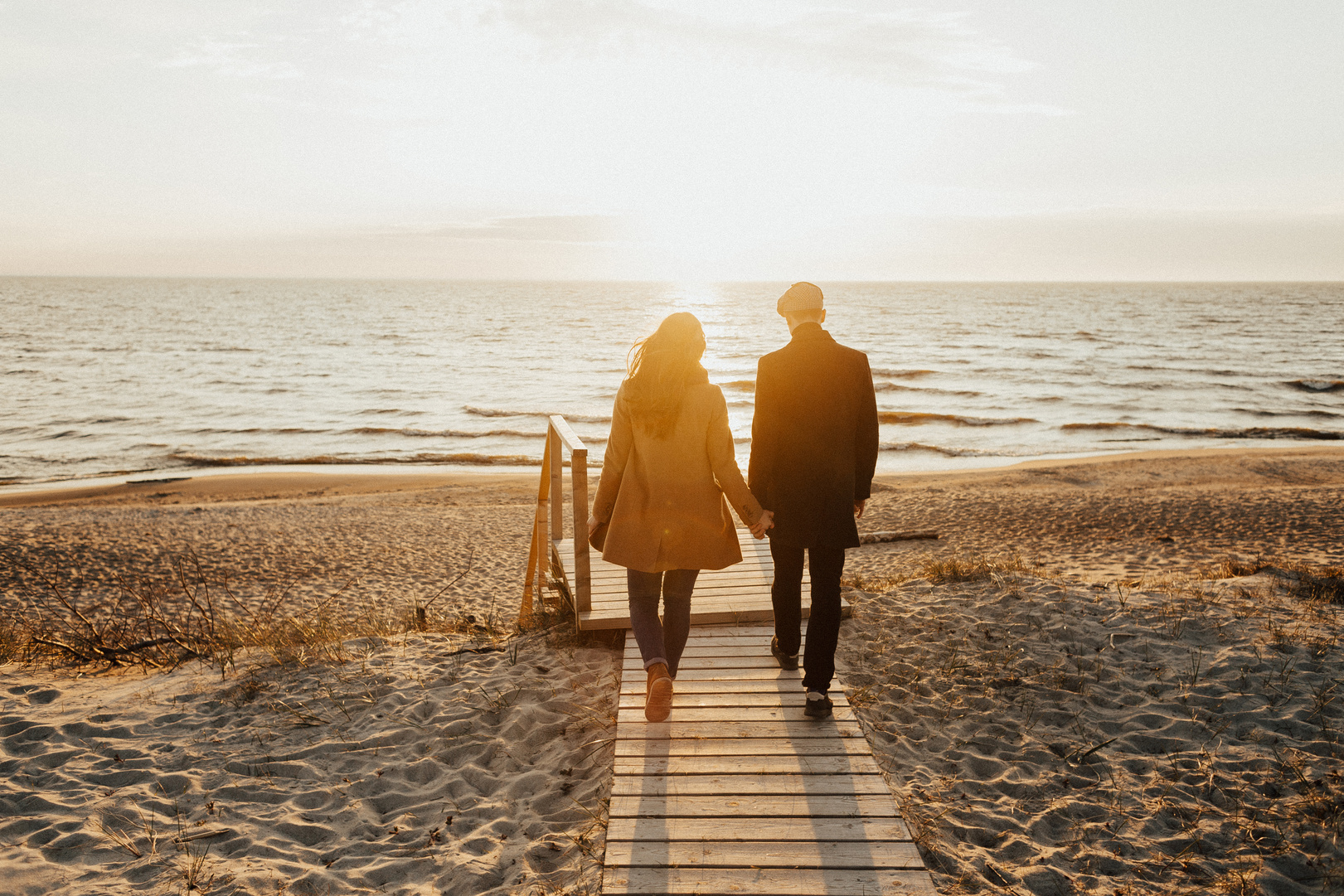 A Couple Walking on a Beach while Holding Hands